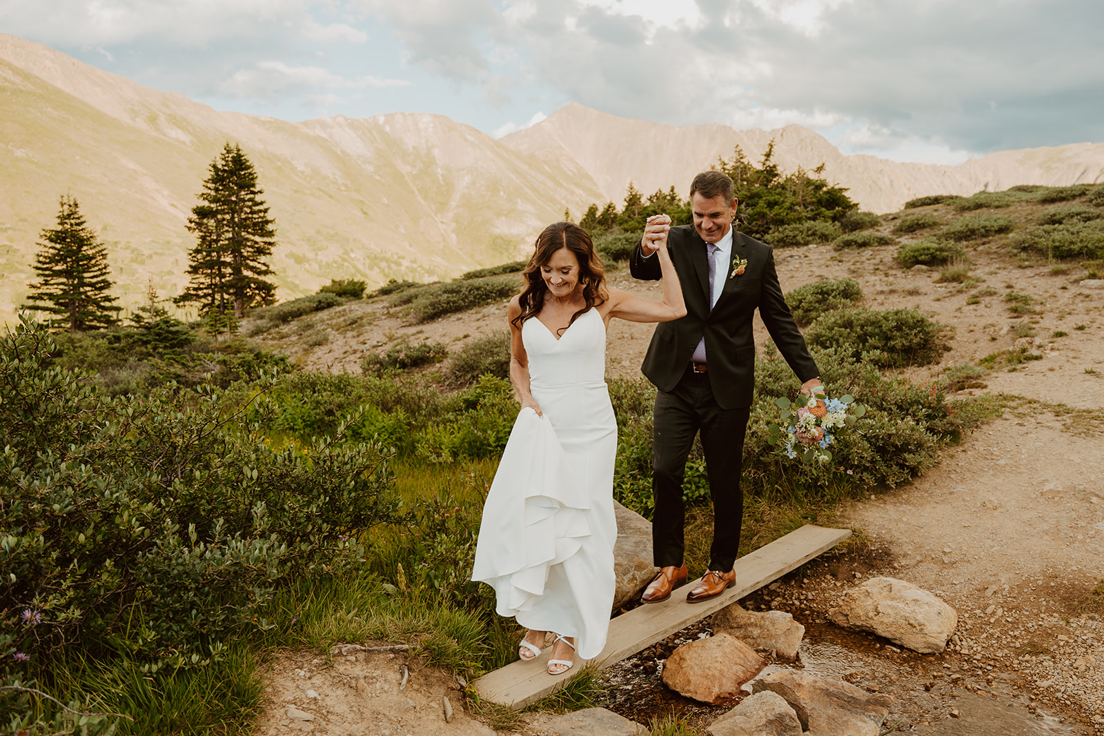 A couple with backpacks on their backs looking out at the mountainscape of the San Juan Mountains in front of them.